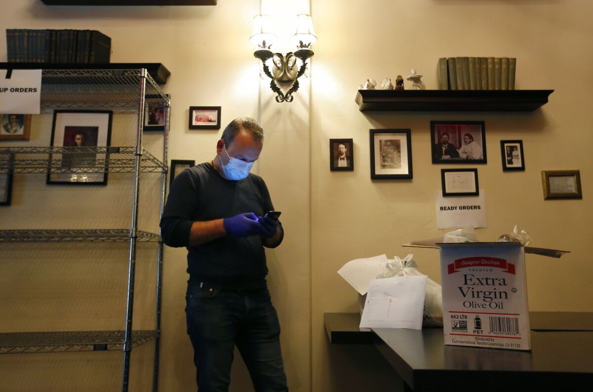 Arthur Gazaryan, who is normally a chef at Pushkin Russian Restaurant in downtown San Diego, looks at his phone as he gets ready to make a delivery of items the restaurant is now selling.