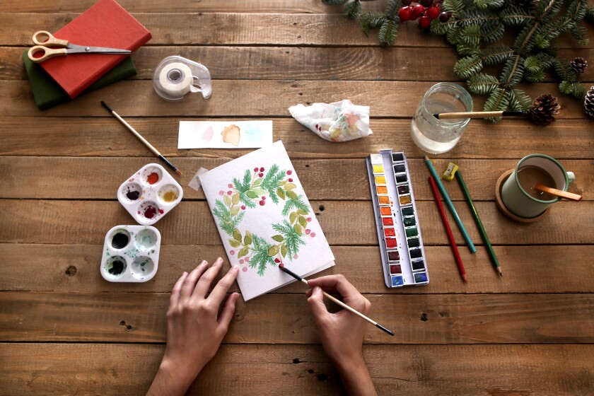 Hands painting stationery on a wooden table
