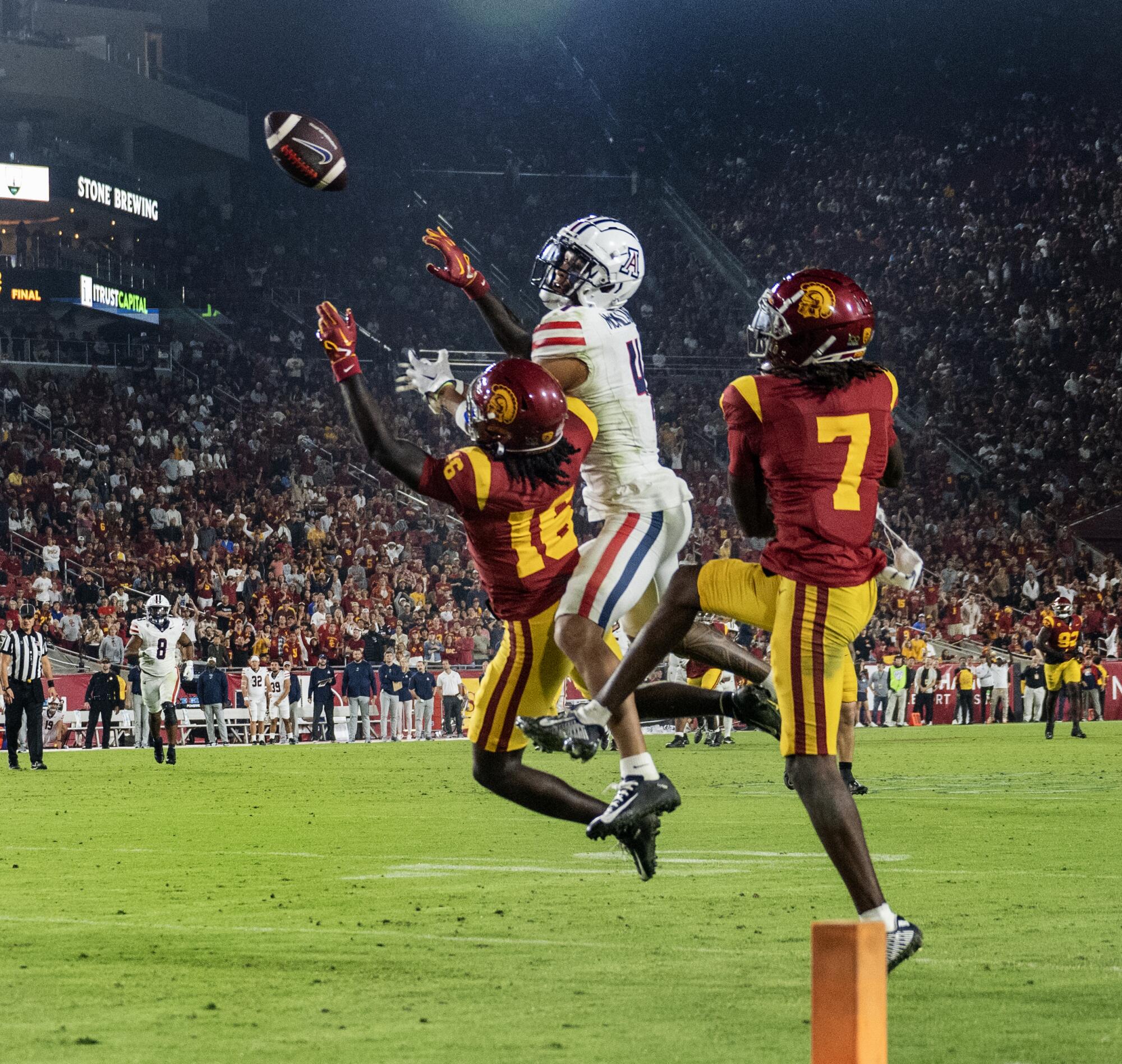 Trojans cornerback Prophet Brown and Calen Bullock leap and break up a pass during a play.
