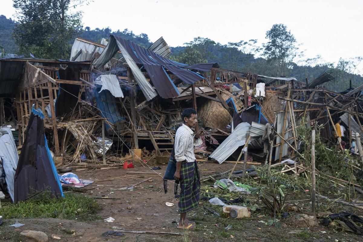 Man outside destroyed homes in a Myanmar displacement camp