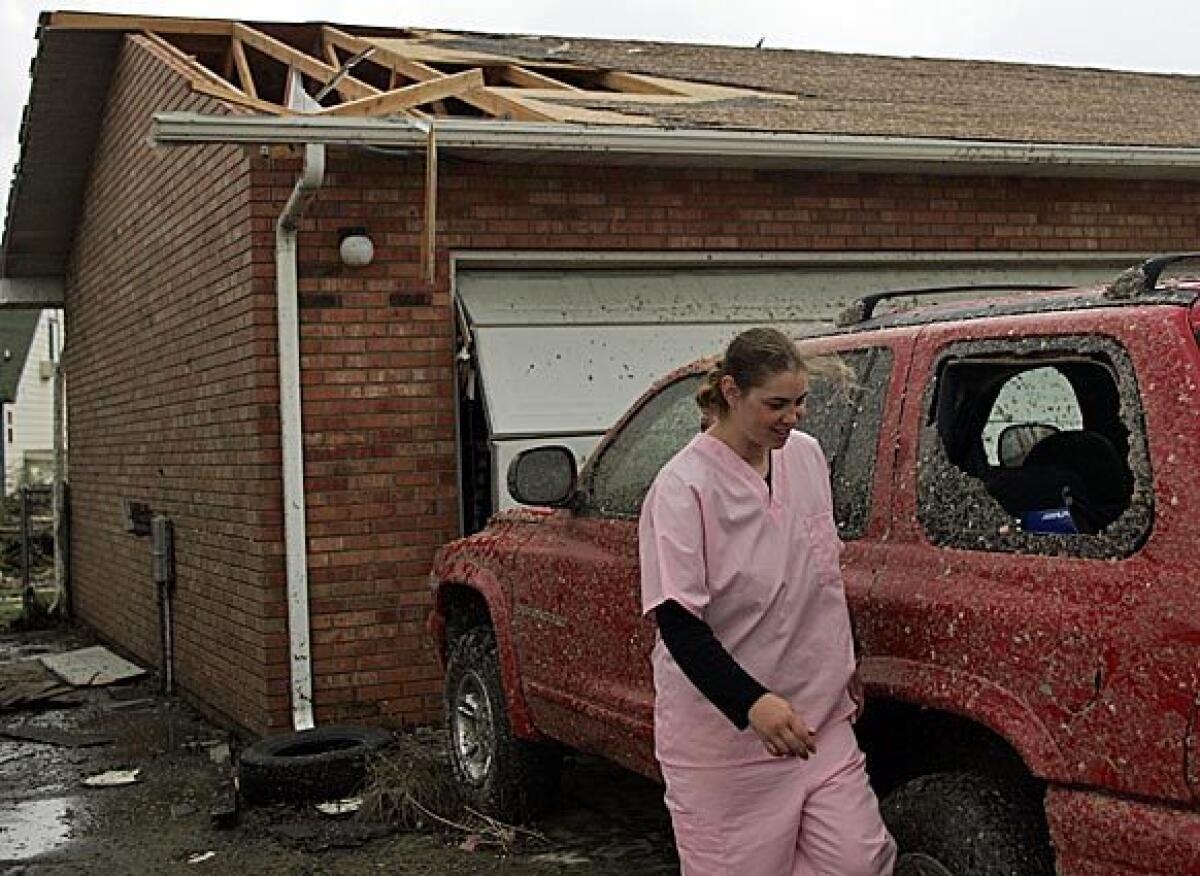 Jenny Adams inspects the damage to her home and vehicle after a tornado hit Windsor.