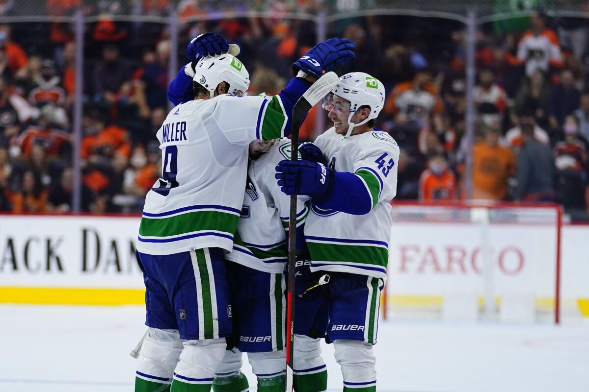 Vancouver Canucks' J.T. Miller, left, celebrates with teammates after scoring a goal during a shootout in an NHL hockey game against the Philadelphia Flyers, Friday, Oct. 15, 2021, in Philadelphia. (AP Photo/Matt Slocum)