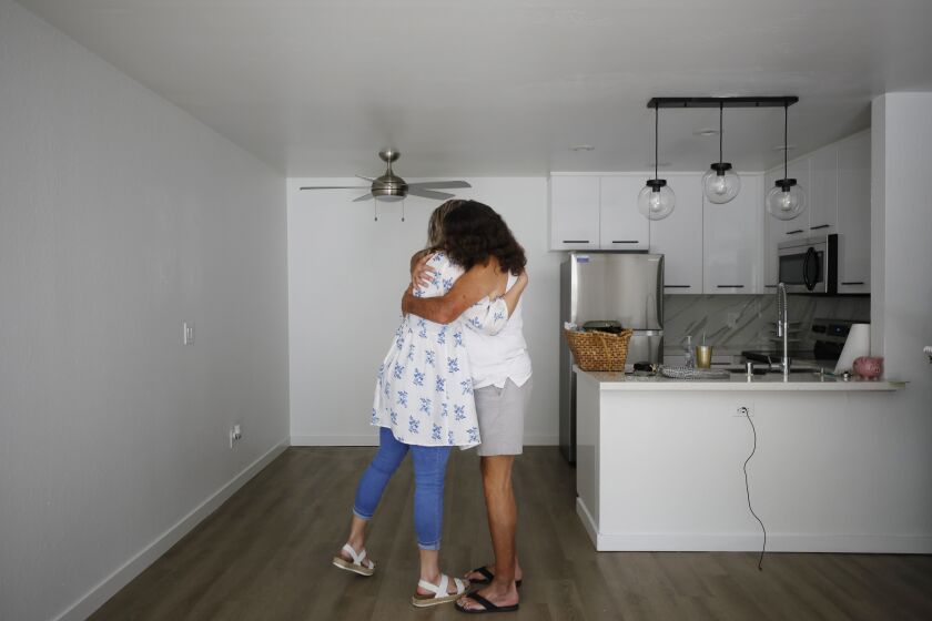 SAN DIEGO, CA - SEPTEMBER 19: Hope Shaw, a housing specialist for PATH (People Assisting The Homeless) hugs Bruce Blackham in his new apartment she arranged for on Monday, September 19, 2022 in San Diego, CA. An Emergency Housing Voucher funded by the American Rescue Plan Act was used to secure an apartment for him. (K.C. Alfred / The San Diego Union-Tribune)
