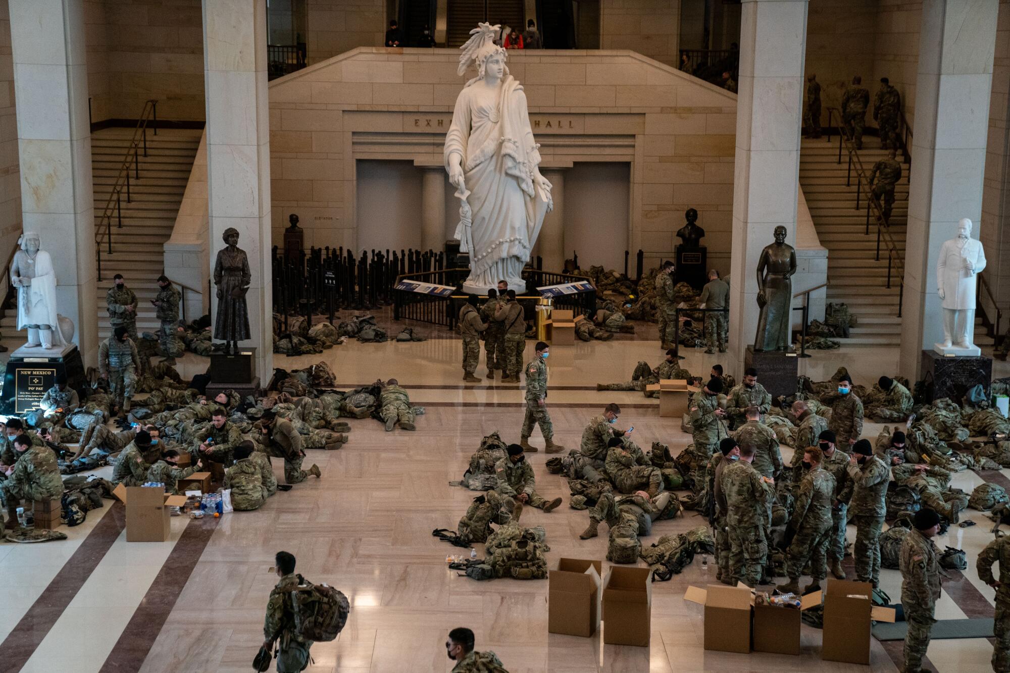 Dozens of troops relax alongside open cardboard boxes and the looming Statue of Freedom plaster cast.