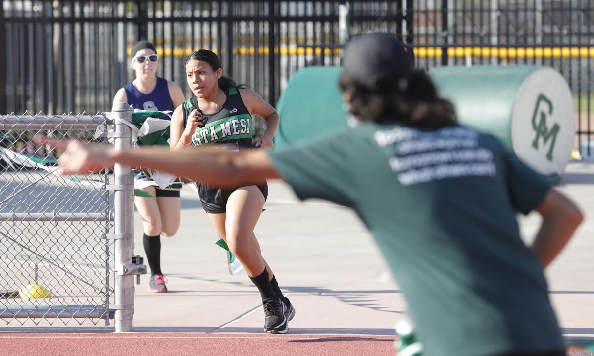 Costa Mesa's Abigail Cahuantzi rounds the turn with encouragement from a friend in a race against Calvary Chapel.