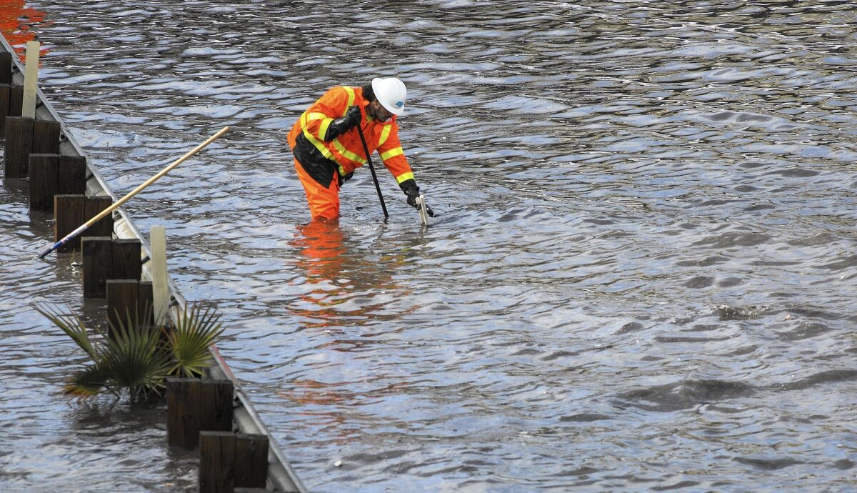 A Caltrans worker toils to clear drains on flooded Interstate 5 in Sun Valley in January.