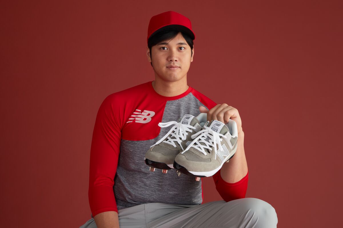 Shohei Ohtani tient une paire de chaussures New Balance.