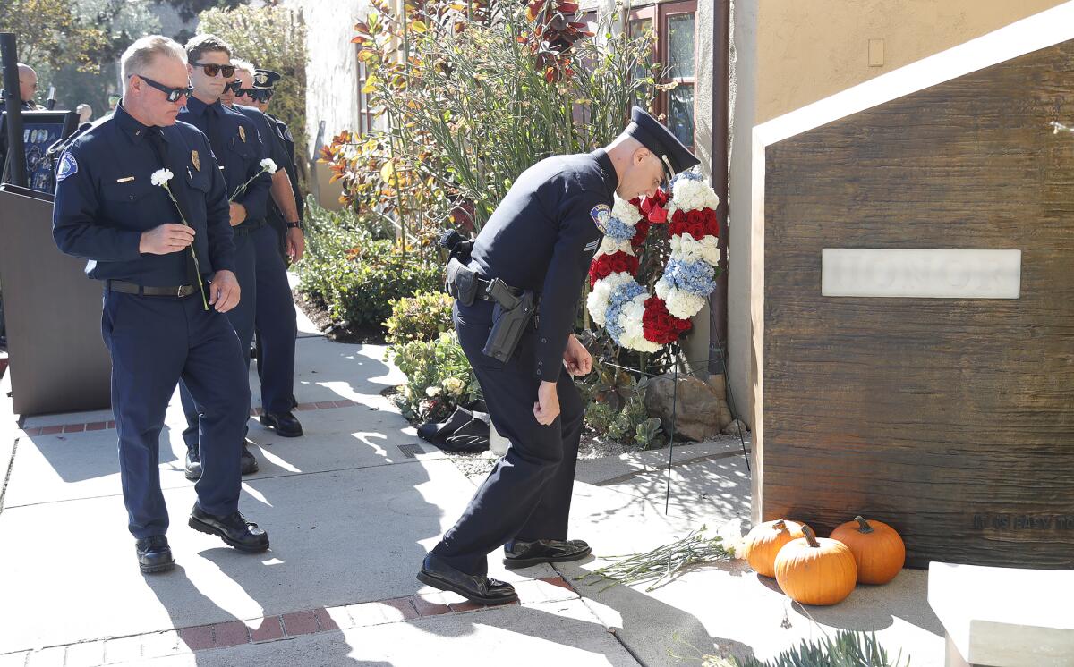 A Laguna Beach police officer lays a flower at the fallen officers memorial wall.