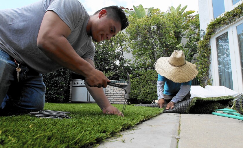 Workers install artificial grass in Pacific Palisades. Despite strong popular demand, the MWD might not have a turf rebate program in the next fiscal year.