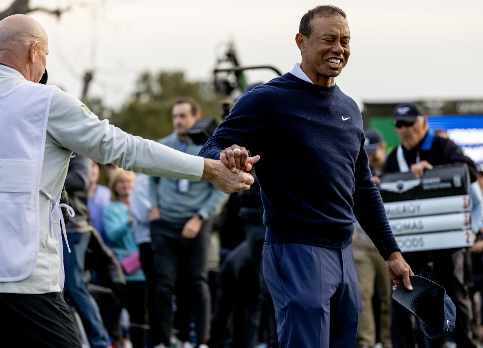Tiger Woods gets a hand shake from his caddy after finishing the first round.
