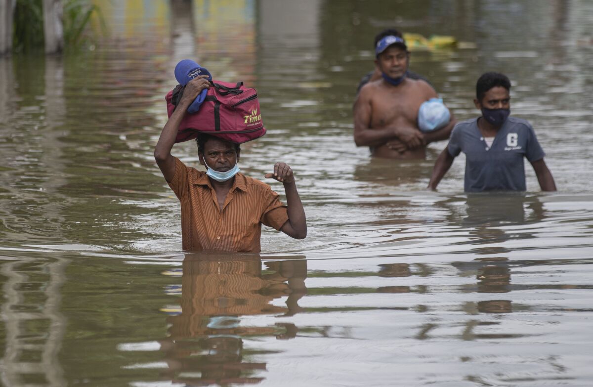 Sri Lankans wade through an inundated street following heavy rainfall at Malwana, on the outskirts of Colombo, Sri Lanka, Saturday, June 5, 2021. Flash floods and mudslides triggered by heavy rains in Sri Lanka have killed at least four people and left seven missing, while more than 5,000 are displaced, officials said Saturday. Rains have been pounding six districts of the Indian Ocean island nation since Thursday night, and many houses, paddy fields and roads have been inundated, blocking traffic. (AP Photo/Eranga Jayawardena)