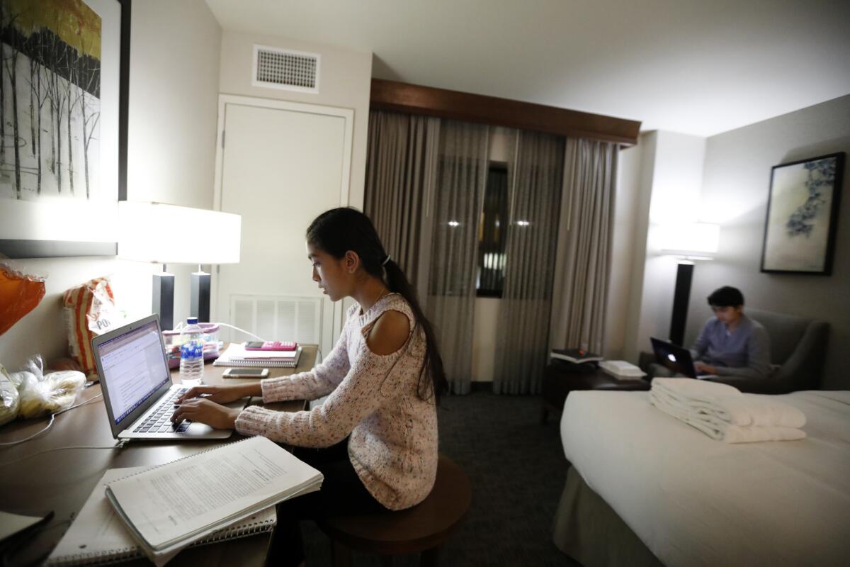 Shanti Raminani, left, and her brother Sathya Raminani, right, do their homework in a hotel in Rosemead. (Francine Orr / Los Angeles Times)