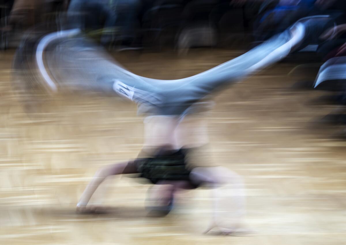 A breakdancer, on his head, is a spinning blur.