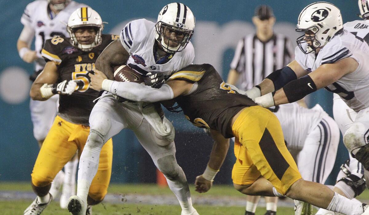 Wyoming's Cassh Maluia tries to stop BYU's Jamaal Williams as he carries the ball in the second quarter of the Poinsettia Bowl on Wednesday.