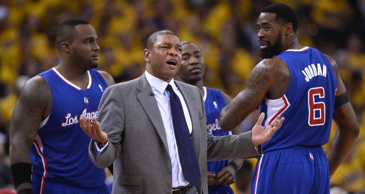 Clippers Coach Doc Rivers argues a call next to players Glen Davis, left, Jamal Crawford, center, and DeAndre Jordan during the team's loss to the Golden State Warriors in Game 4 of the Western Conference quarterfinals Sunday. Rivers says he and his players must find a way to deal with the scandal surrounding owner Donald Sterling as the team continues its postseason trek.