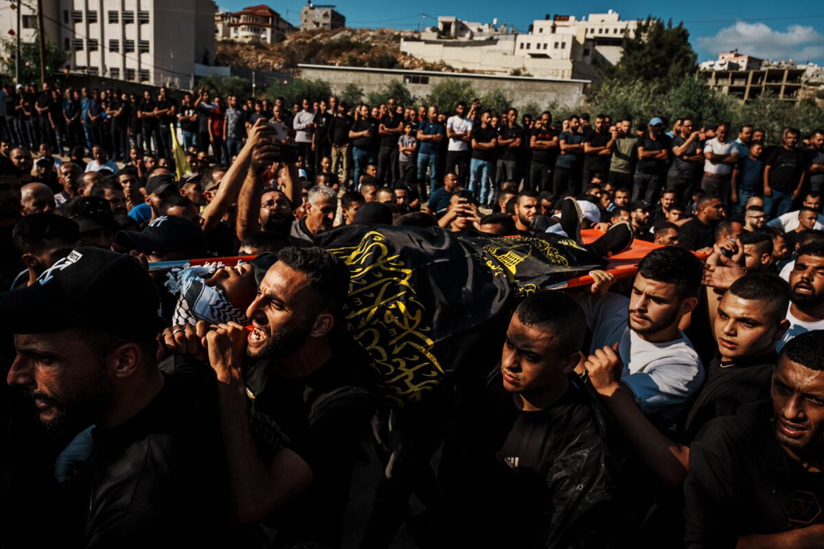 Mourners carry the nine bodies of thirteen Palestinians killed in an Israeli assault on the Nour Shams refugee camp