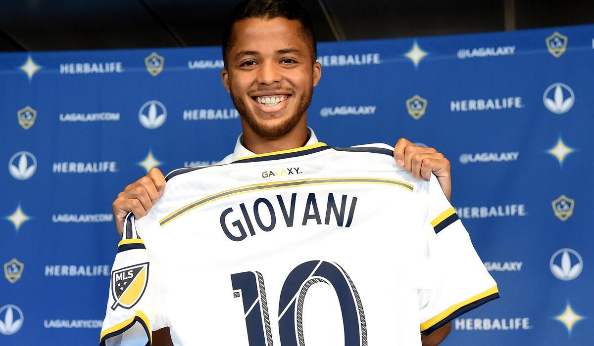 Galaxy's Giovani Dos Santos holds up his new jersey at a press conference at StubHub Center on Tuesday.