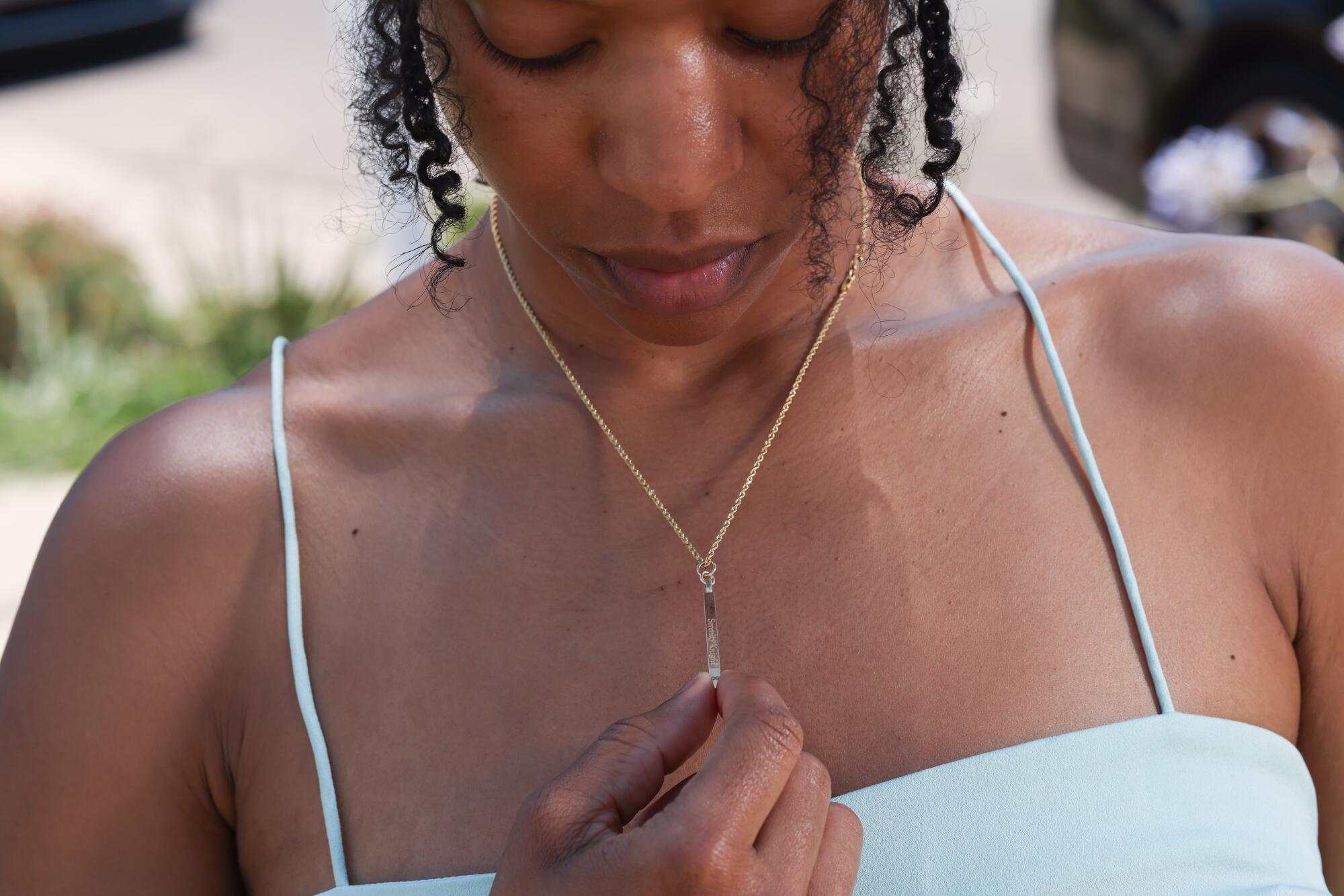 Michelle Mitchenor looks down as she touches a necklace she's wearing 