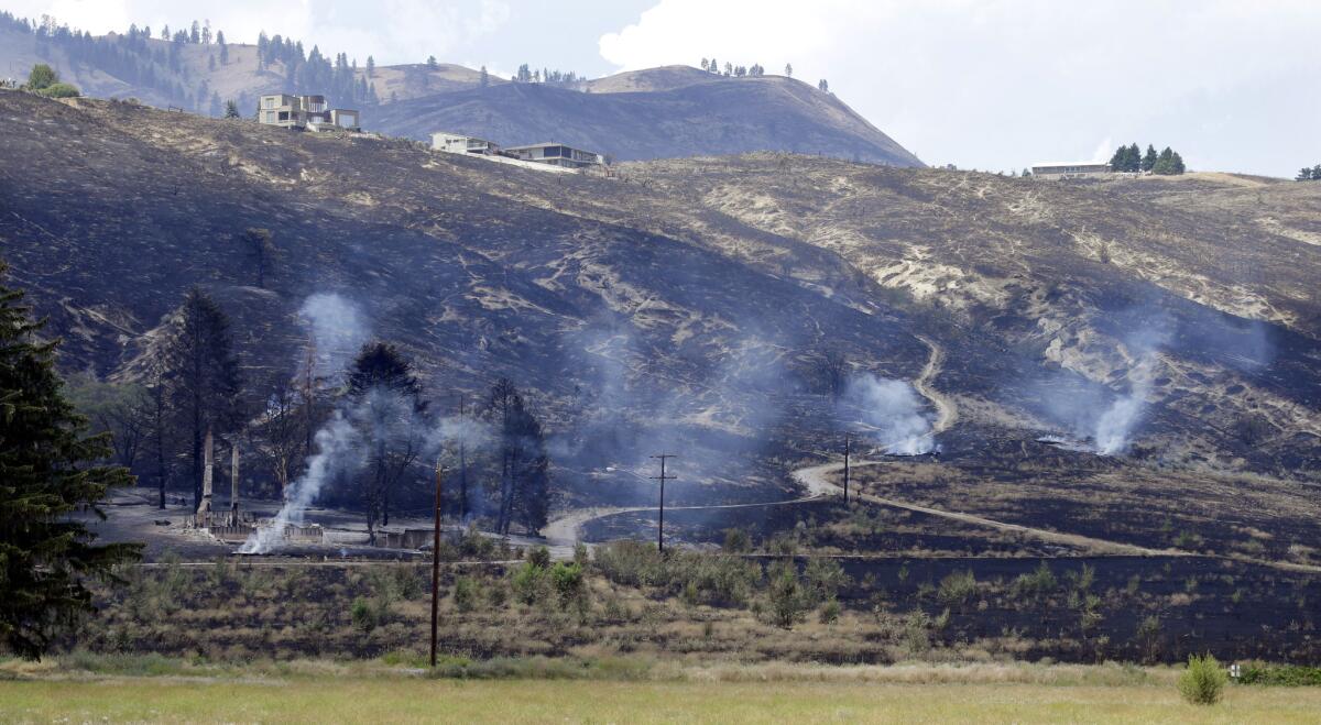 The foundation and chimneys from a destroyed home continue to smolder from a wildfire that raced through the area the night before, June 29, 2015, in Wenatchee, Wash. The wildfires hit parts of central and eastern Washington over the weekend as the state is struggling with a severe drought.