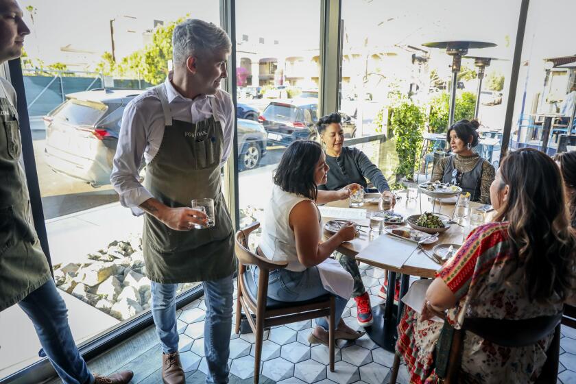 SAN DIEGO, CA-MAY 9: Waitor Miguel Diaz goes over the menu with customers at Fort Oak Restaurant on Thursday, May 9, 2024 in Mission Hills. Governor Gavin Newsom signed a law targeting hidden fees, including surcharges that many restaurants have tacked on to their bills for several years to cover the increasing cost of labor and goods.(Photo by Sandy Huffaker for The SD Union-Tribune)