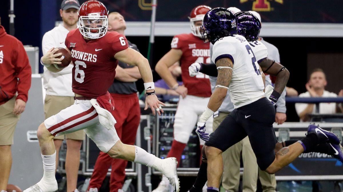 Oklahoma quarterback Baker Mayfield, left, gains yardage as he runs the ball as TCU safety Niko Small (2) gives chase in the first half of the Big 12 Conference championship on Saturday.