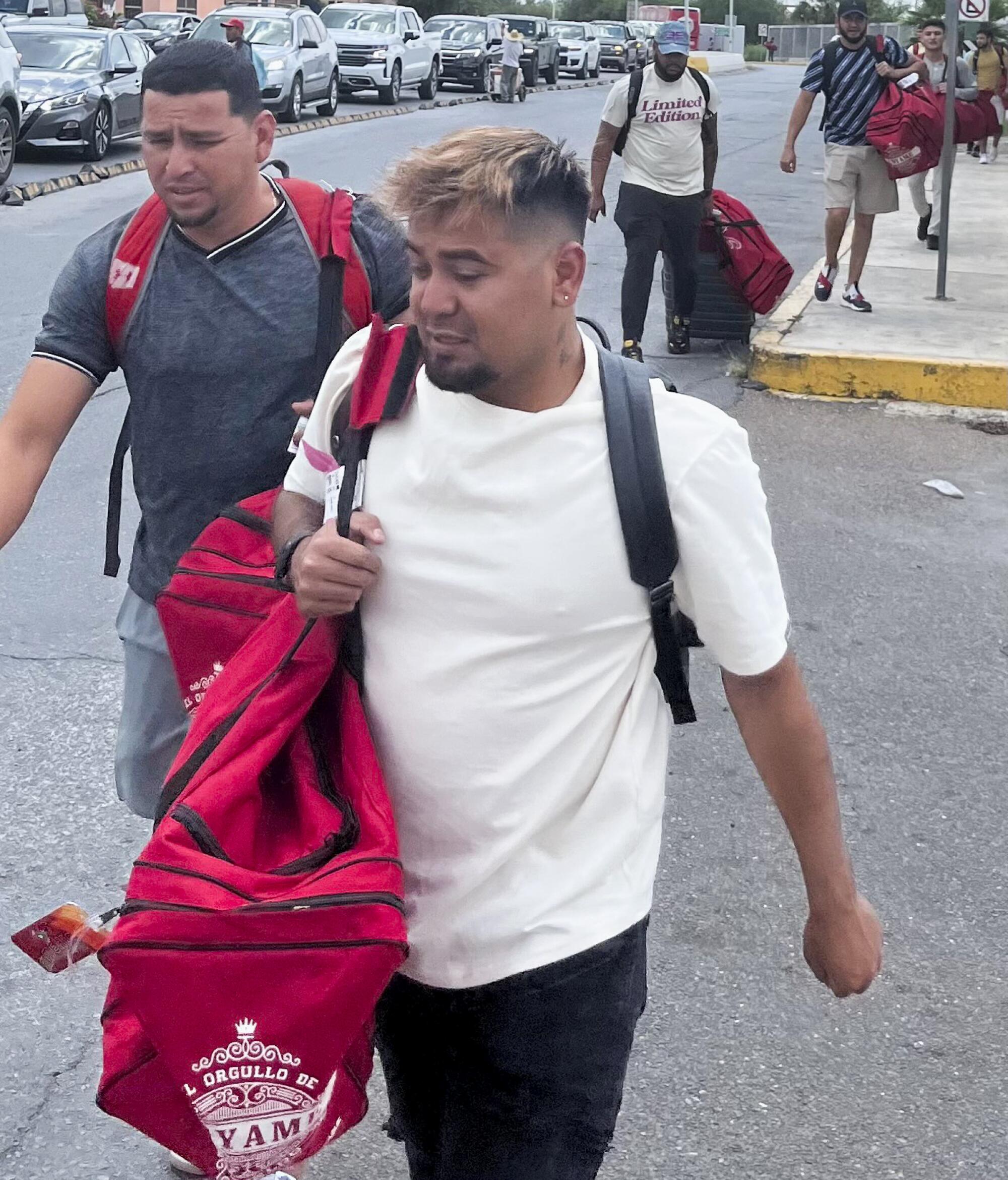 Veracruz players Christian Zazueta, left, and Samuel Zazueta carry their equipment bags toward a bridge.