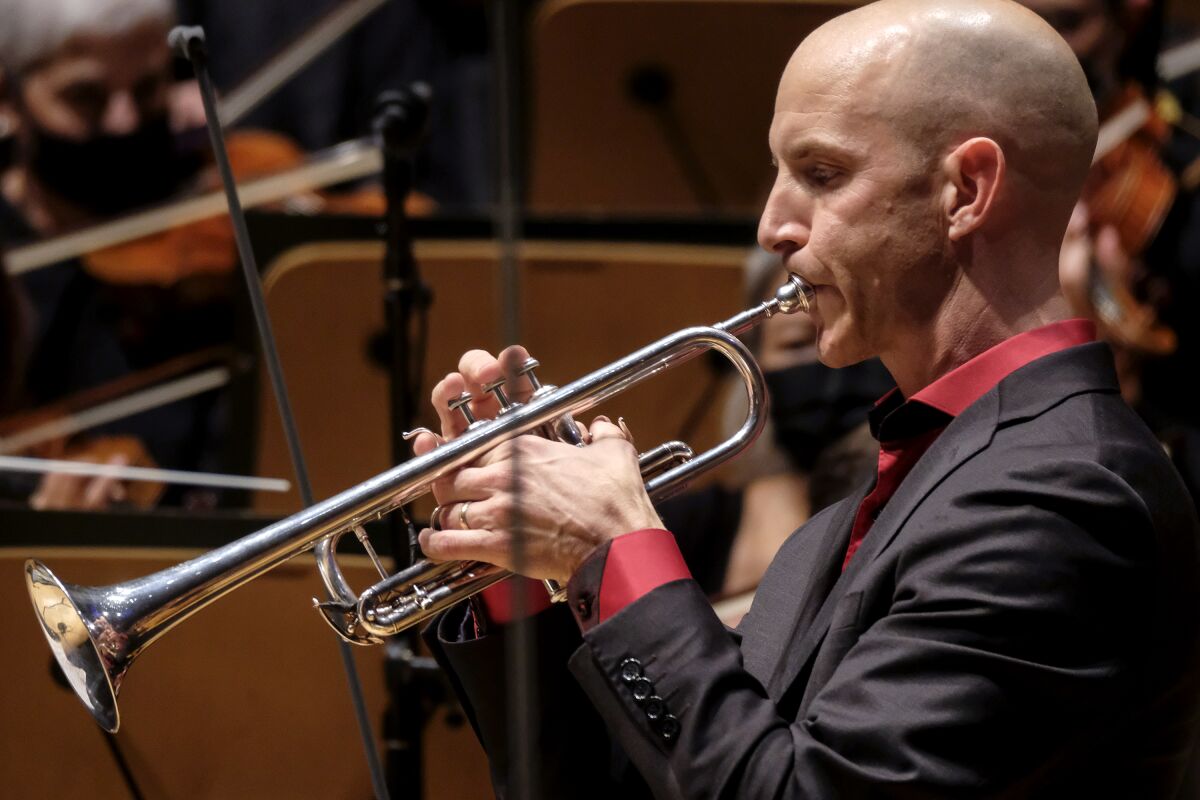 A man plays a trumpet in concert.