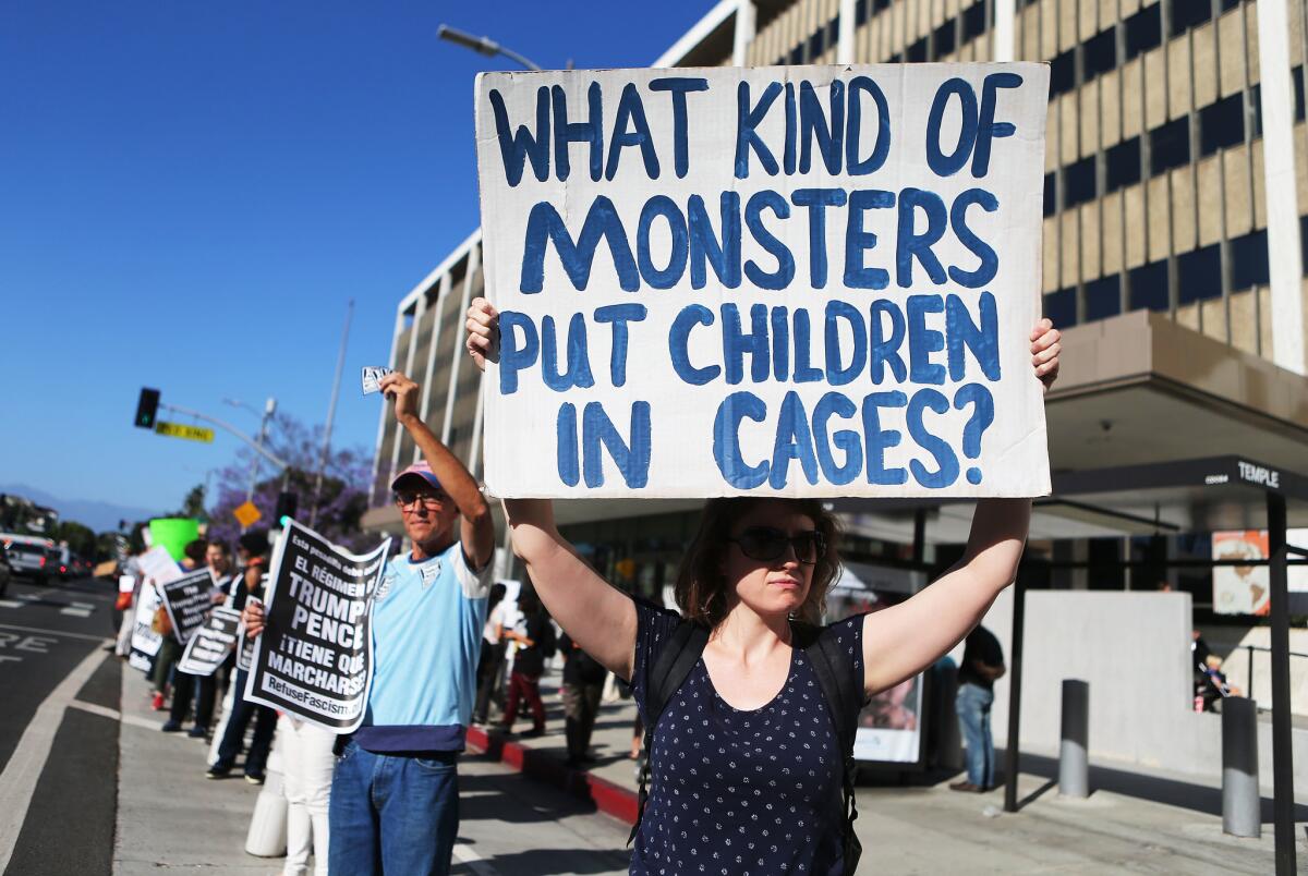 A protester outside L.A. federal building two years ago holds a sign reading, "What kind of monsters put children in cages?"