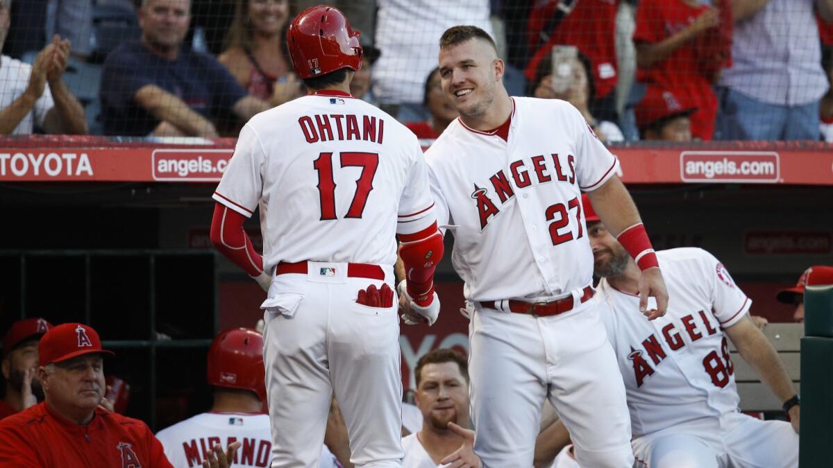 Angels' Shohei Ohtani shakes hands with Mike Trout after hitting a home run.