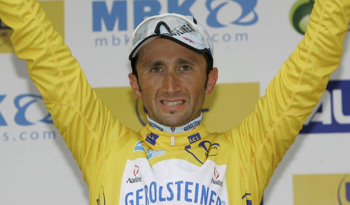 FILE - Italy's Davide Rebellin smiles on the podium as he wears the yellow jersey after the sixth stage of the Paris-Nice cycling race in Cannes, southern France, on March 15, 2008. Italian cyclist Davide Rebellin, one of cycling’s longest-serving professionals, was reportedly killed on Wednesday, Nov. 30, 2022 after being struck by a truck while training. He was 51. (AP Photo/Lionel Cironneau, File)