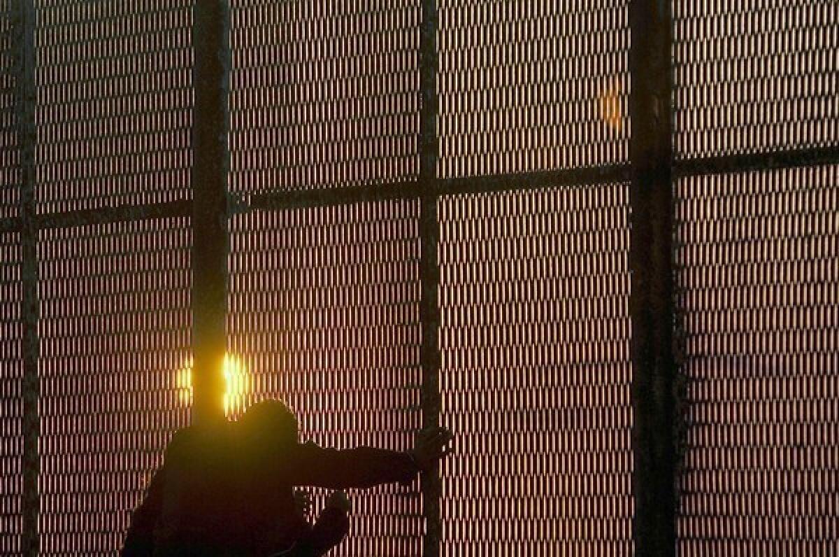 As the sun sets, a man pauses at the security fence along the U.S.-Mexico border near Tijuana.