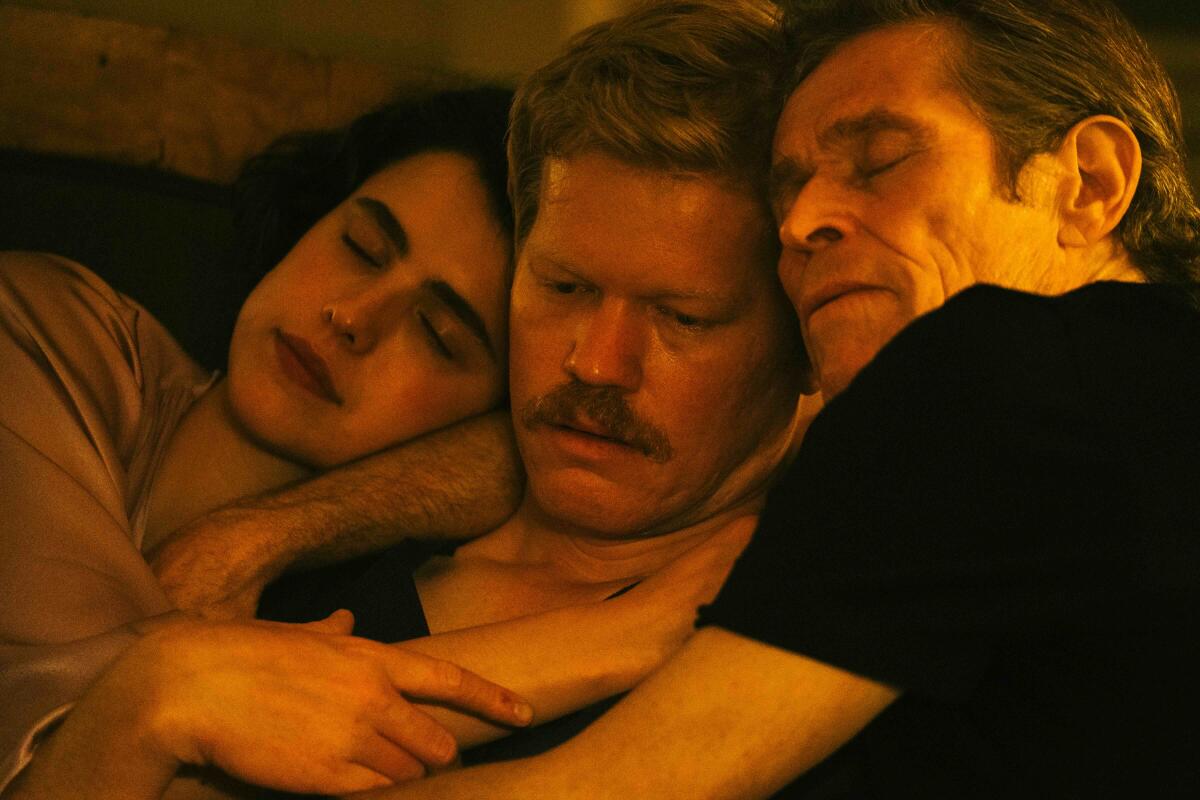 Three people embrace on a couch.