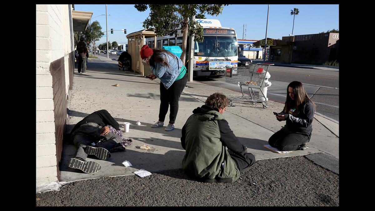 City Net volunteer and licensed vocational nurse Angie Munoz, left, and lead case manager Jennifer Munoz speak with homeless men in the 1800 block of Placentia Avenue in Costa Mesa during the 2019 Point in Time homeless count.