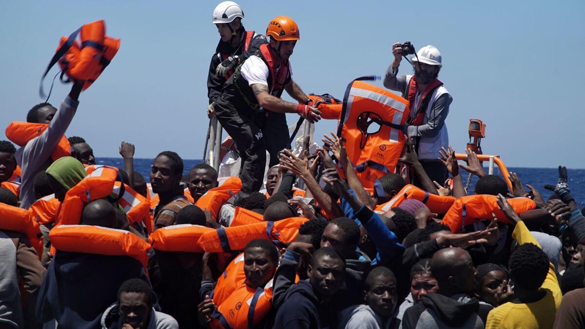 Rescue workers disembark migrants from a dinghy in the Mediterranean Sea.
