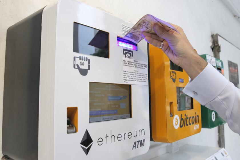 FILE - In this Friday, May 11, 2018 file photo, a man uses an Ethereum ATM next to a bitcoin ATM, in Hong Kong. A Swiss region that has billed itself as a hub for high-tech finance says it plans to accept cryptocurrencies Bitcoin and Ether for tax payments starting next year. Switzerland’s Zug canton promotes itself as home to “Crypto Valley,” and it is thought to be the first region in the rich Alpine country to make the decision announced Thursday, Sept. 3, 2020. (AP Photo/Kin Cheung, file)
