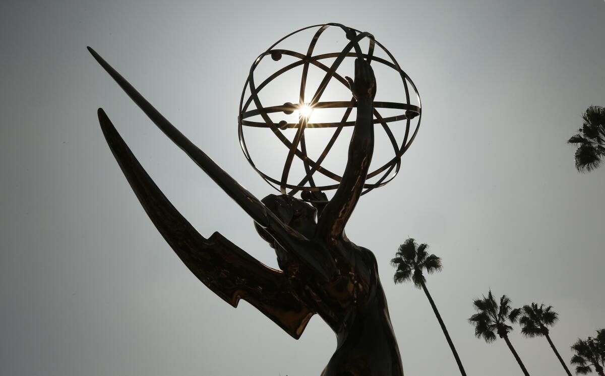 A large Emmy Award statue in silhouette with palm trees in the background