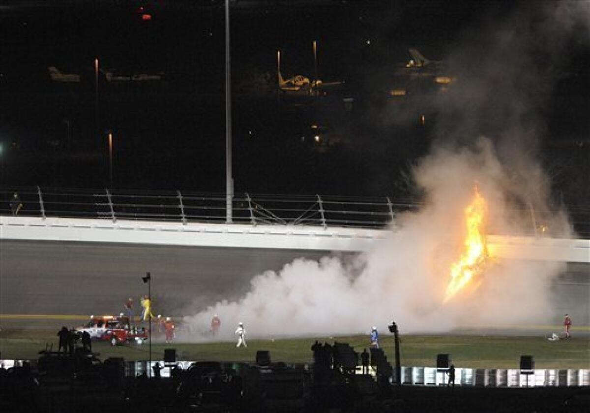 Crews work to put out a fire on car driven by Juan Pablo Montoya, of Colombia, as flames rise from jet fuel spilling on the track after Montoya collided with a jet dryer during a caution period in the NASCAR Daytona 500 auto race at Daytona International Speedway in Daytona Beach, Fla., Monday, Feb. 27, 2012. (AP Photo/Phelan M. Ebenhack)