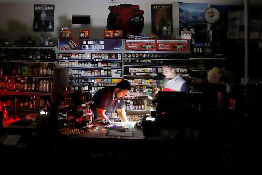 HEALDSBURG, CALIF. - OCT. 26, 2019. Shopekeepers Sodhi Singh, left, and Navneet Singh prepare to close down their gas station and convenience store after the lights went out in Healdsburg at about 8 p.m. on Saturday night, Oct. 26, 2019, ahead of an expected high wind event in the area of the Kincade fire. (Luis Sinco/Los Angeles Times)