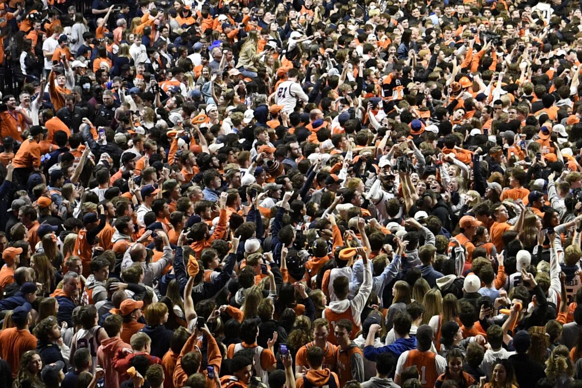 A sea of fans storm the court at the conclusion of a college basketball game in Illinois.