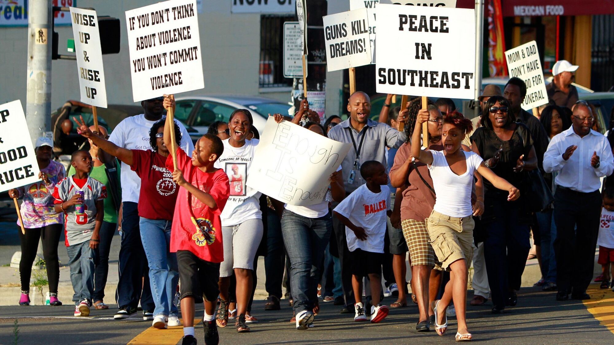 Residents carried held signs and chanted in a rally against violence at the intersection of Euclid and Imperial avenues.