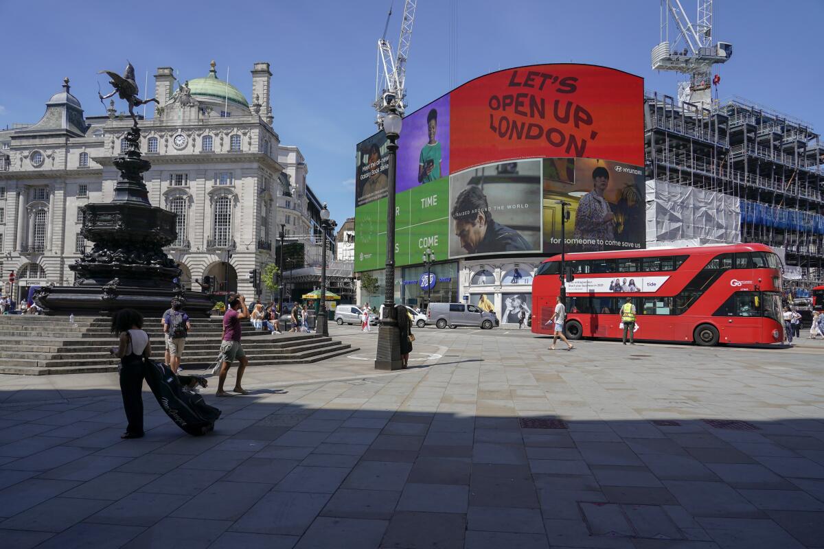 People walk in Piccadilly Circus, in London, Monday, June 14, 2021. British Prime Minister Boris Johnson is expected to confirm Monday that the next planned relaxation of coronavirus restrictions in England will be delayed as a result of the spread of the delta variant first identified in India. (AP Photo/Alberto Pezzali)