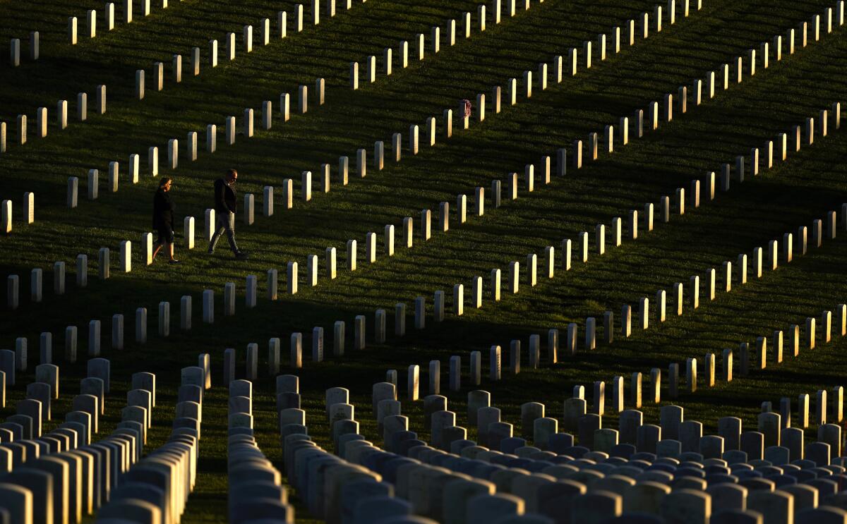 A couple walks among graves at Fort Rosecrans National Cemetery on Veterans Day in San Diego. 