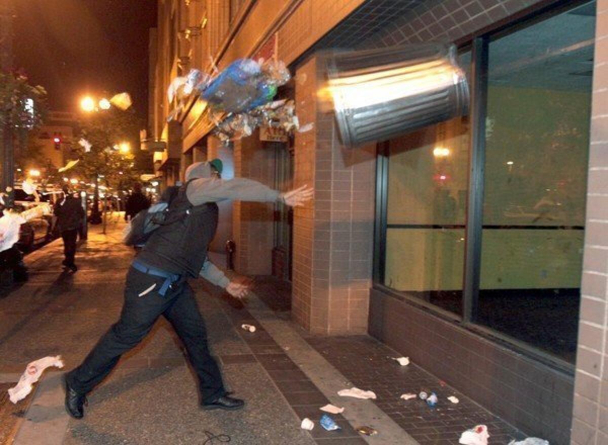 A man throws a trash can at the window of a building during a protest in Oakland early Sunday after George Zimmerman was found not guilty in the shooting death of Trayvon Martin.