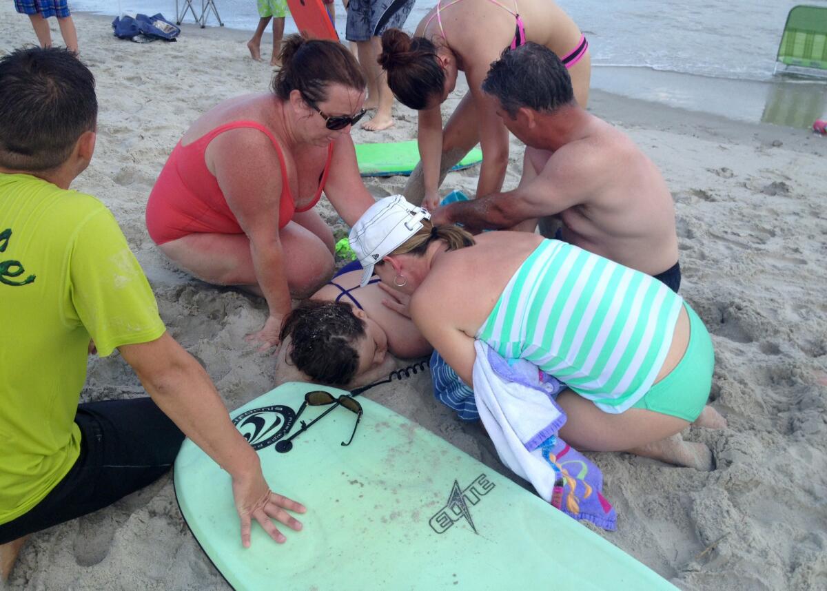 People assist a girl at the scene of the first of two shark attacks Sunday in Oak Island, N.C.
