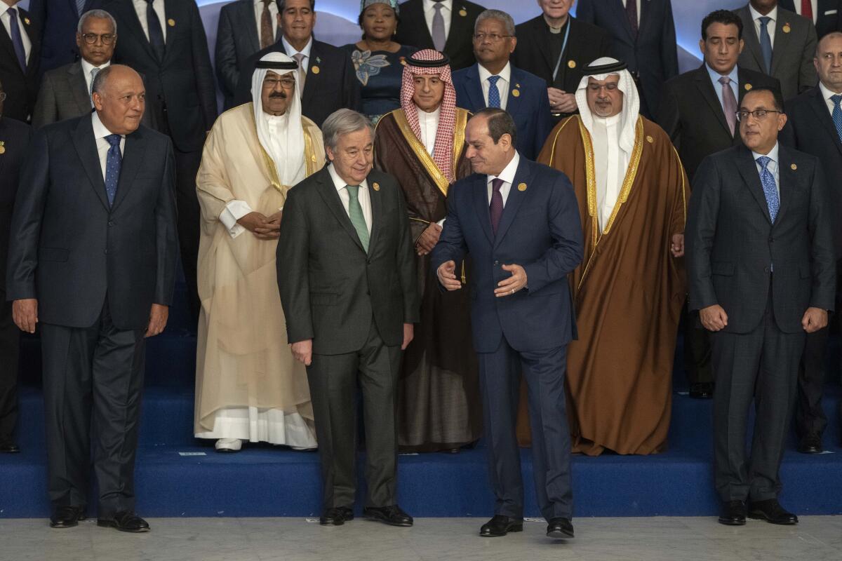 Men in business suits and Middle Eastern thawbs take their places for a group photo