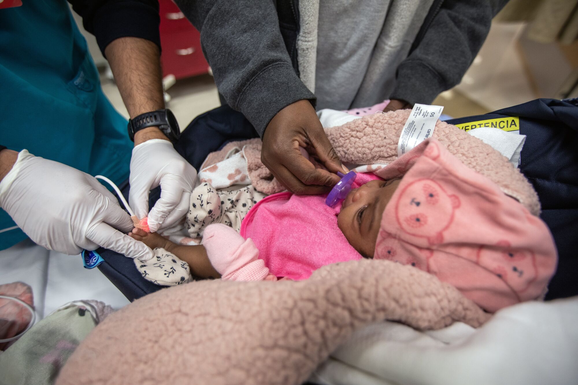 Un bébé est assis pendant que sa mère et un agent de santé s'occupent d'elle