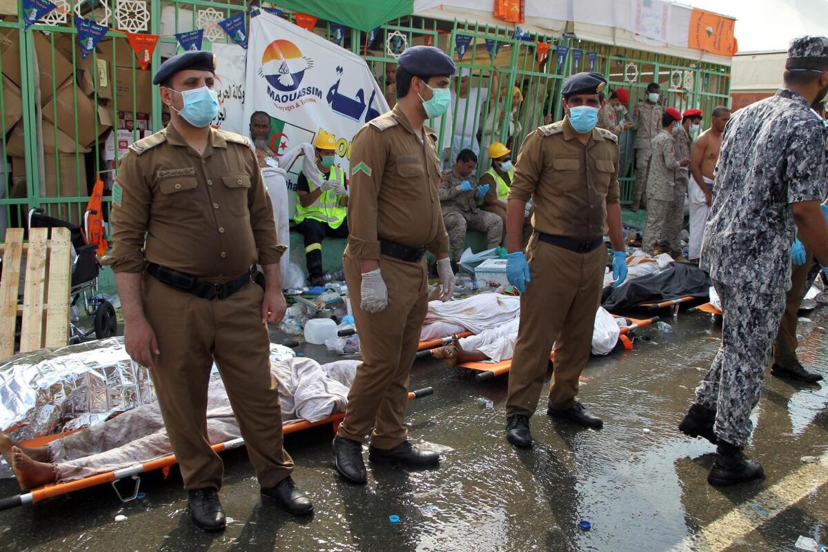 Saudi emergency personnel stand near bodies of Hajj pilgrims at the site where at least 717 were killed and hundreds injured in a stampede in Mina.