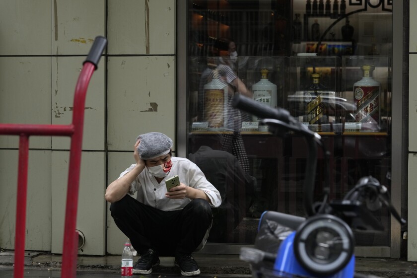 A restaurant cook wearing a mask takes a break out on the sidewalk, Monday, June 27, 2022, in Beijing. (AP Photo/Ng Han Guan)