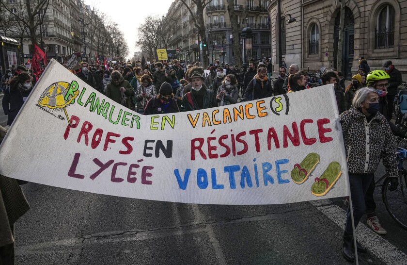 Demonstrators mach with a banner that reads that reads "Blanquer on holidays teachers on resistance Voltaire high school" during a protest in Paris, Thursday, Jan 20, 2022. France's education minister Jean-Michel Blanquer faced calls to resign after regretting the "symbolism" of a holiday escape to Ibiza, where he announced a strict Covid testing protocol for students that sparked a fierce backlash from teachers. (AP Photo/Michel Euler)