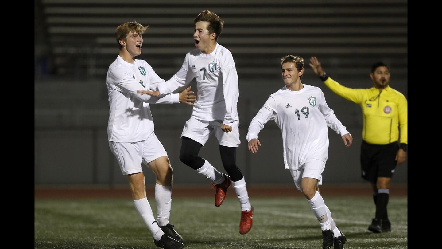 Edison High's Armand Pigeon, center, reacts after scoring on a direct free kick with teammates Raymond Drake, left, and Dylan Lybarger, right, during the first half of the Adidas West Coast Showcase opener at Downey Warren on Thursday, December 13, 2018.